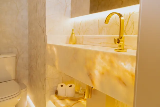 Lavabo com bancada retroiluminada e metais dourados