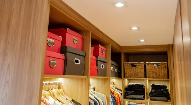 Closet em madeira com nichos para caixas e iluminação embutida