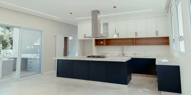 Cozinha ampla com ilha azul-marinho e armários brancos até o teto