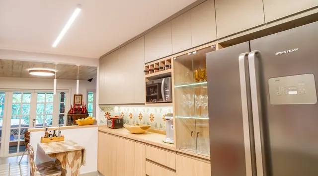 Cozinha em madeira clara com cristaleira iluminada