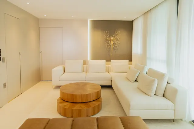 Sala de estar com painel em tom areia e mesas de centro em madeira